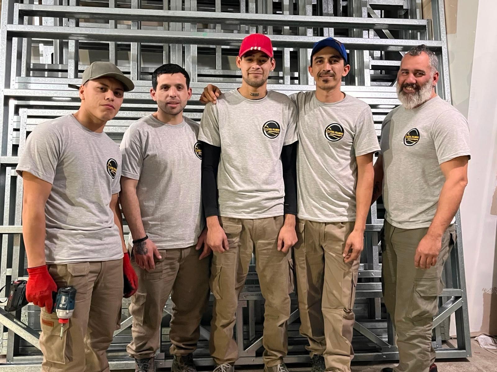 Equipo de obra de EcoHome frente a una estructura de steel frame